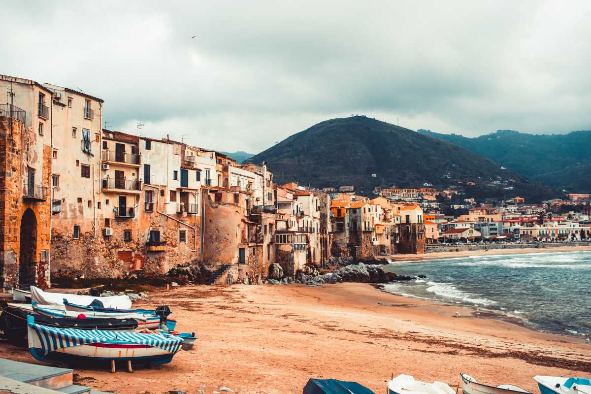 Scorcio di una piazza di Cefalù addobbata per una festa tradizionale serale, bandiere colorate, luci e gente del posto